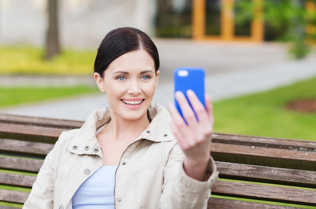 koncepcja napojów, wypoczynku, technologii i ludzi - uśmiechnięta kobieta robi zdjęcie smartfonem w parku