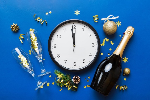Zdjęcie koncepcja obchodów nowego roku z butelką szampana i dwoma kieliszkami opiekania boże narodzenie pudełko z budzikiem i gałązką jodły na kolorowym stole widok z góry miejsce na kopiowanie