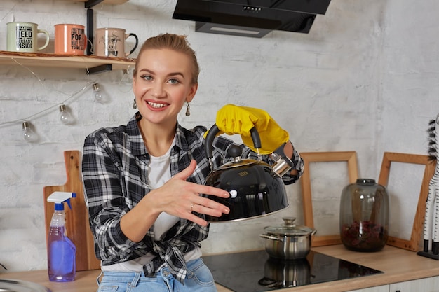 Koncepcja obsługi domowej i sprzątania szczęśliwa blondynka sprzątająca czajnik kuchenny