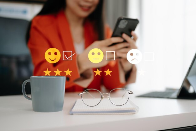 Koncepcja oceny obsługi klienta Kobieta biznesu naciskająca na twarz uśmiech pokaz emotikon na wirtualnym ekranie na tabletie i smartfonie w biurze