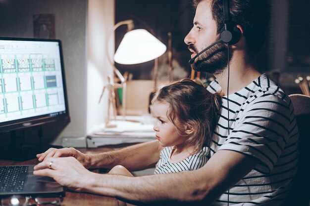 koncepcja ojcostwa pracujący ojciec z córeczką i laptopem w domowym biurze