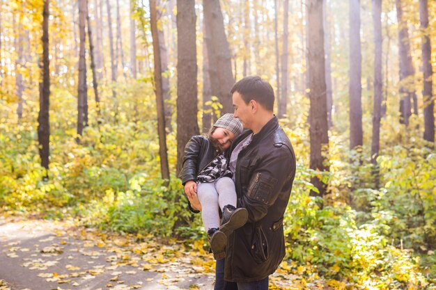 Koncepcja ojcostwa, rodziny i wypoczynku - ojciec trzymający córeczkę w ramionach w jesiennym parku