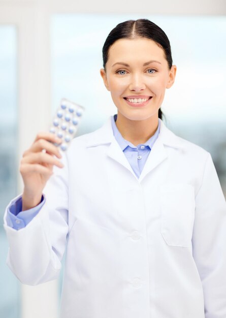 koncepcja opieki zdrowotnej, farmacji i medycyny - uśmiechnięty młody lekarz z tabletkami w szafce