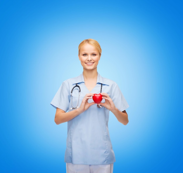 Zdjęcie koncepcja opieki zdrowotnej i medycyny - uśmiechnięta lekarka lub pielęgniarka z sercem i stetoskopem