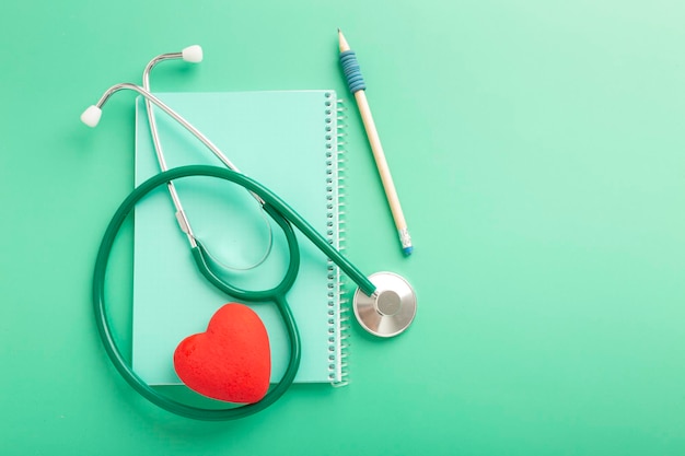 Zdjęcie koncepcja opieki zdrowotnej i zdrowego stylu życia góra nad głową z bliska widok zdjęcia czarnego stetoskopu i małego czerwonego serca na białym tle na tle stołu z kopią pustą pustą przestrzeń