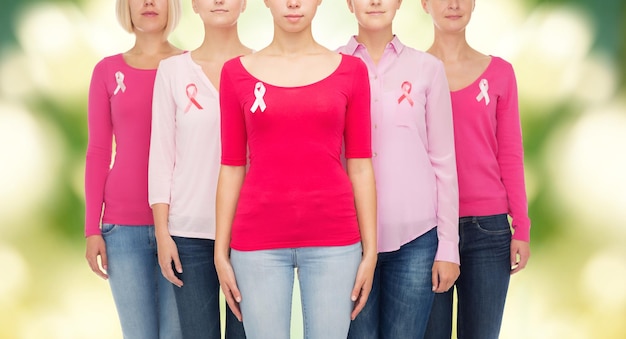 Zdjęcie koncepcja opieki zdrowotnej, ludzi i medycyny - zbliżenie kobiet w pustych koszulach z różowymi wstążkami świadomości raka piersi na zielonym tle