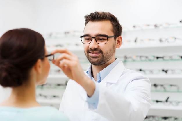 koncepcja opieki zdrowotnej, ludzi, wzroku i wzroku - optyk zakłada okulary kobiecie w sklepie optycznym