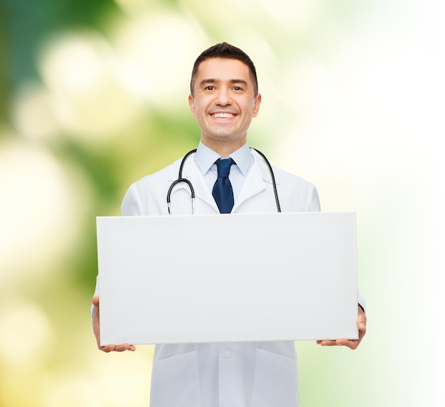 koncepcja opieki zdrowotnej, reklamy, ludzi i medycyny - uśmiechnięty mężczyzna lekarz w białym fartuchu trzymający białą pustą tablicę na zielonym tle