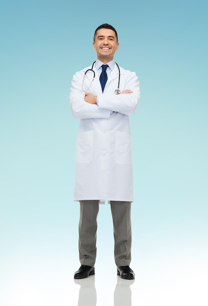 koncepcja opieki zdrowotnej, zawodu, ludzi i medycyny - uśmiechnięty mężczyzna lekarz w białym fartuchu na niebieskim tle