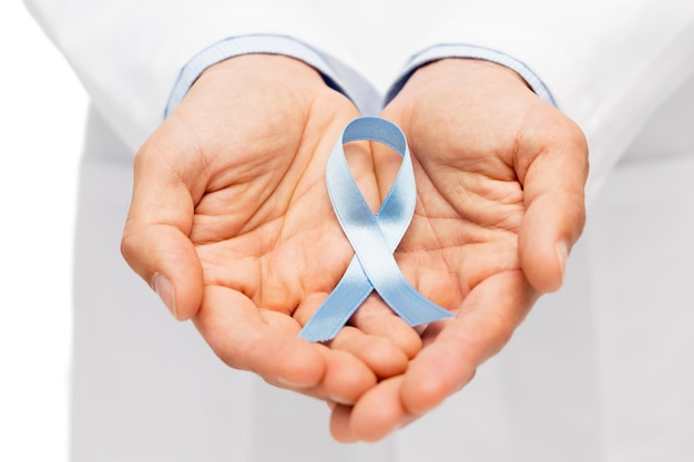 koncepcja opieki zdrowotnej, zawodu, ludzi i medycyny - zbliżenie męskich rąk lekarza trzymającego niebieską wstążkę świadomości raka prostaty