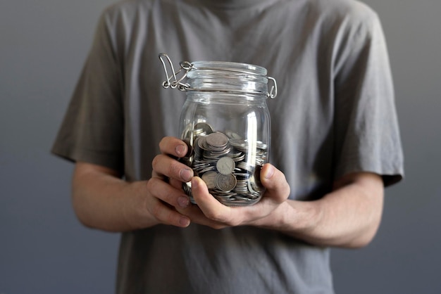 Koncepcja oszczędności trzymająca szkło z pieniędzmi monet