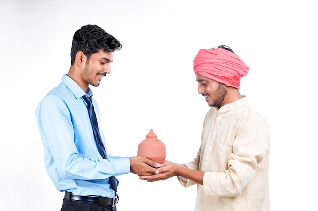 Koncepcja oszczędzania: młody indyjski bankier i rolnik trzymający w ręku glinianą skarbonkę
