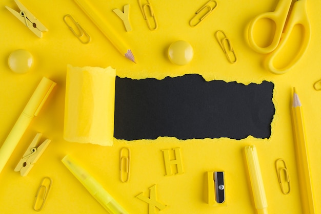 Zdjęcie koncepcja papeterii z powrotem do szkoły. góra nad widokiem z góry zbliżenie zdjęcia żółtej papeterii i rozdartego jasnożółtego papieru na czarnym tle z copyspace
