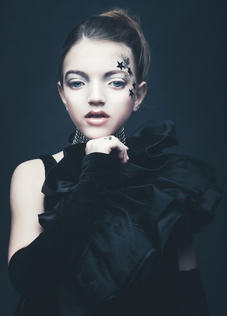 Koncepcja piękna i mody Mała dziewczynka ubrana w czarny strój Kreatywny makijaż
