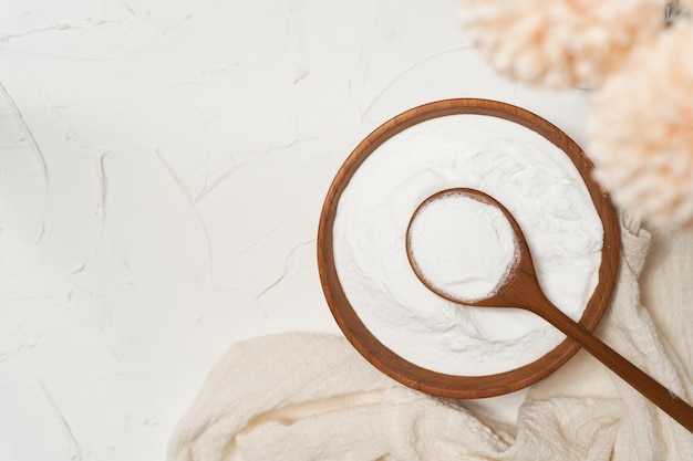 koncepcja piękna proszku kolagenu w drewnianej misce i łyżką na tle biały stół.
