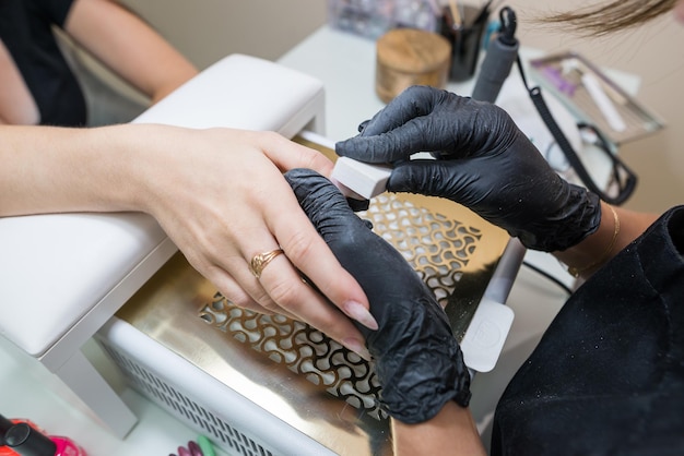 Koncepcja pielęgnacji paznokci Manikiurzystka wykonuje manicure klientce w salonie kosmetycznym