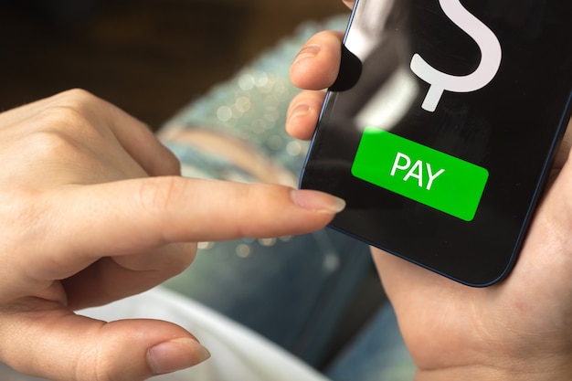 Koncepcja płatności online, przycisk płatności na ekranie, kobieta pozywa smartfona i korzysta z aplikacji bankowości internetowej, zdjęcie koncepcji e-commerce