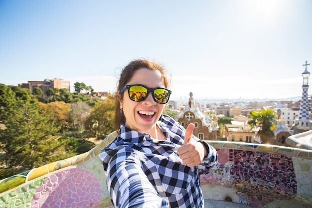 Koncepcja podróży i wakacji - młoda kobieta szczęśliwa co selfie portret ze smartfonem w Park Guell