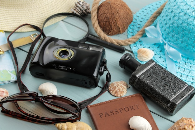 Koncepcja podróży Kapelusz, aparat fotograficzny, paszport, mapa i okulary przeciwsłoneczne na drewnianym niebieskim stole.