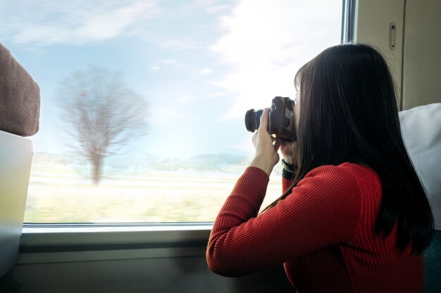 Koncepcja podróży. Młoda Podróżna kobieta z kamerą bierze fotografię podczas gdy siedzący w pociągu