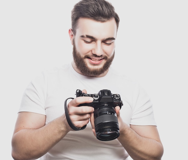 Koncepcja podróży, technologii i stylu życia: młody brodaty fotograf robienia zdjęć aparatem cyfrowym.