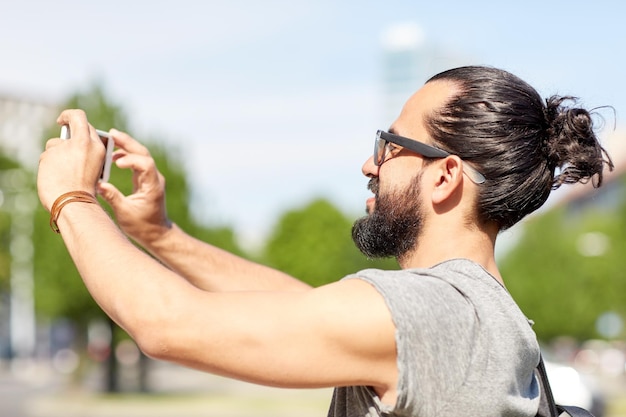 koncepcja podróży, turystyki, technologii i ludzi - uśmiechnięty mężczyzna nagrywający wideo lub selfie smartfonem na letniej ulicy miasta