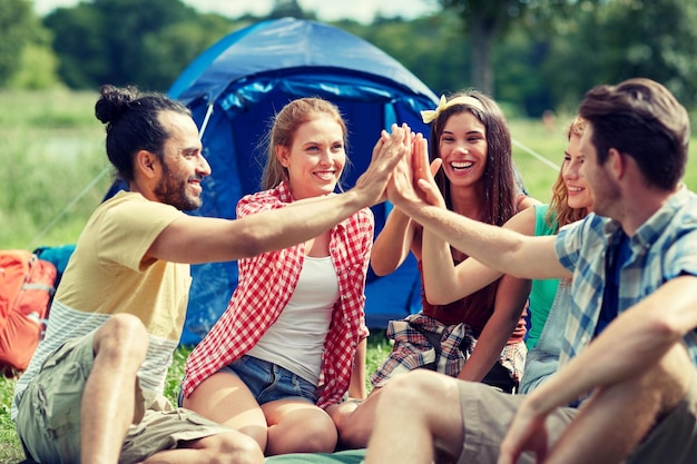 koncepcja podróży, turystyki, wędrówek i ludzi - grupa szczęśliwych przyjaciół z namiotem przybijająca piątkę na kempingu