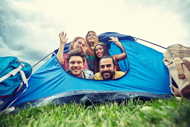 koncepcja podróży, turystyki, wędrówek, sprzętu i ludzi - grupa szczęśliwych przyjaciół z plecakami w namiocie na kempingu