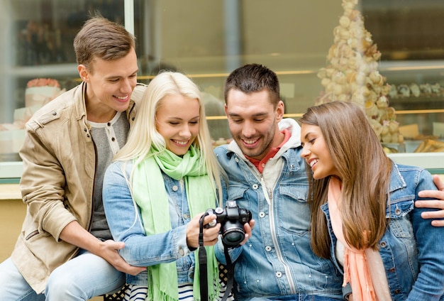 koncepcja podróży, wakacji, technologii i przyjaźni - grupa uśmiechniętych przyjaciół z cyfrowym aparatem fotograficznym w mieście