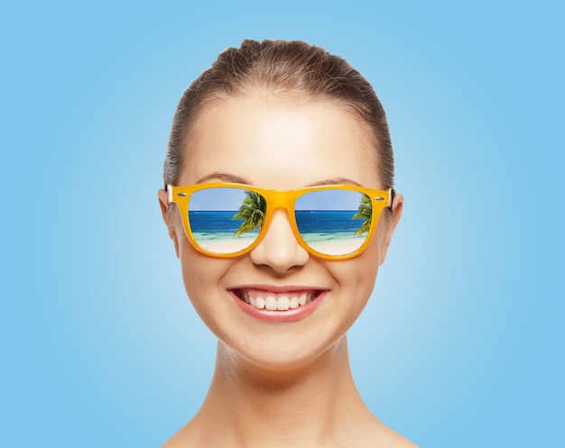 koncepcja podróży, wakacji, wakacji i szczęśliwych ludzi - portret szczęśliwej nastolatki w okularach przeciwsłonecznych z odbiciem na plaży