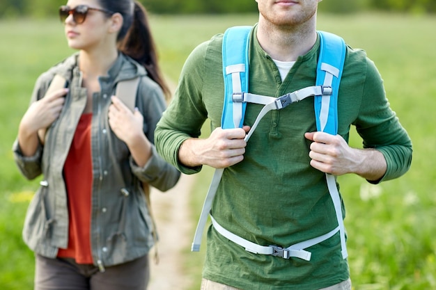 Zdjęcie koncepcja podróży, wędrówek, wędrówek z plecakiem, turystyki i ludzi - zbliżenie pary z plecakami idącymi wiejską drogą