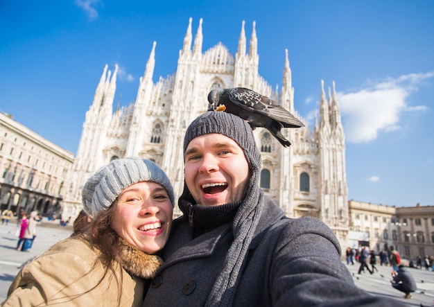 Koncepcja podróży, Włochy i zabawna para - szczęśliwi turyści biorący autoportret z gołębiami przed katedrą Duomo, Mediolan