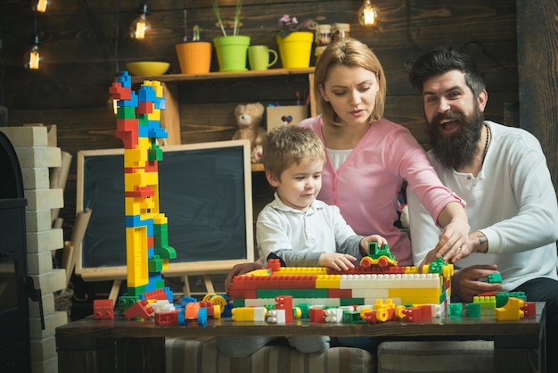 Koncepcja pokoju zabaw. Małe dziecko bawi się klockami w pokoju zabaw. Syn z matką i ojcem budują model konstrukcji w pokoju zabaw. Zabawa w pokoju zabaw