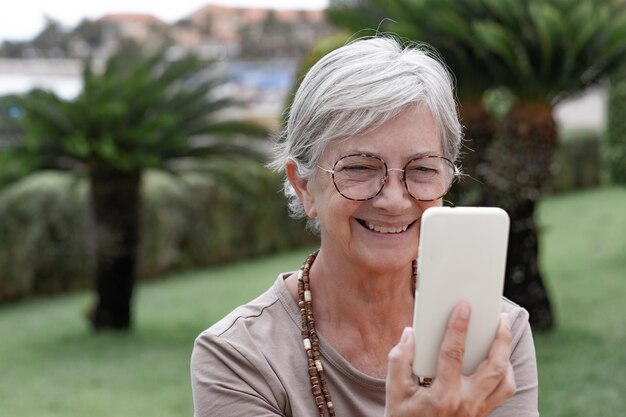 Koncepcja połączenia wideo Portret szczęśliwej starszej kobiety korzystającej z czatu wideo za pomocą telefonu komórkowego