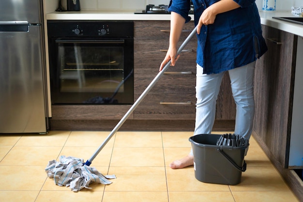 Zdjęcie koncepcja pracy w gospodarstwie domowym uśmiechnięta młoda kobieta w codziennych ubraniach myje drewnianą podłogę laminowaną