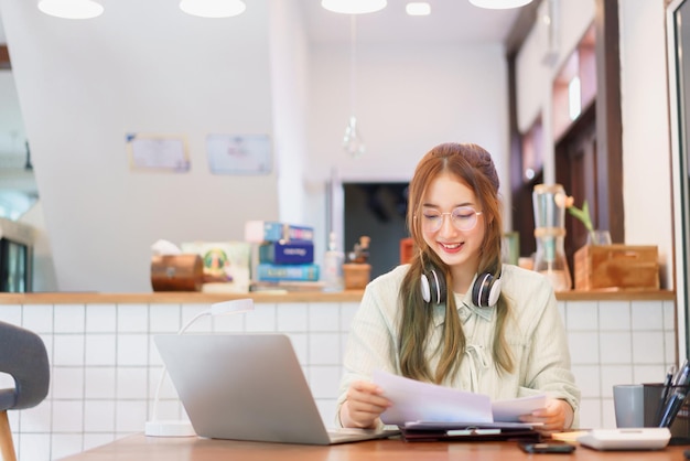 Koncepcja pracy zdalnej Kobieta przedsiębiorca czytająca dokument i pracująca na laptopie w przestrzeni coworkingowej