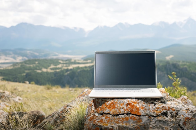 Koncepcja pracy zdalnej laptopa na naturalnym kamieniu w górach