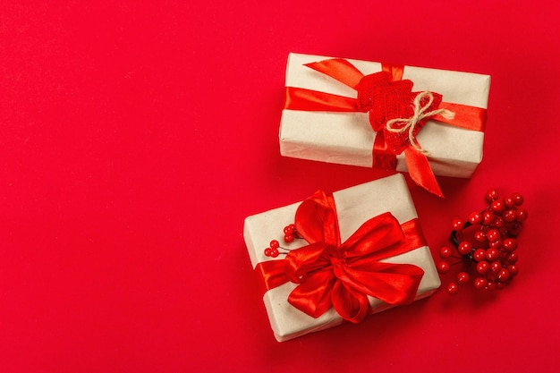 Koncepcja prezentu w czerwonych kolorach. Nowy Rok lub Boże Narodzenie, świąteczny nastrój. Owinięte pudełka, minimalistyczny design, czerwone szorstkie teksturowane tło, widok z góry