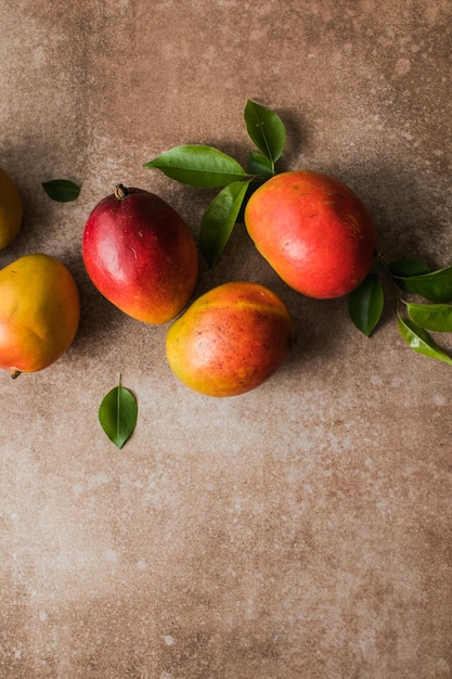 Zdjęcie koncepcja projektu tła mango widok z góry świeżego wzoru owoców mango z liśćmi na stole