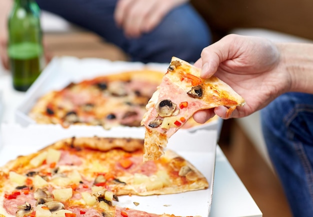 koncepcja przyjaźni, alkoholu, ludzi, uroczystości i wakacji - zbliżenie męskich przyjaciół pijących piwo i jedzących pizzę w domu