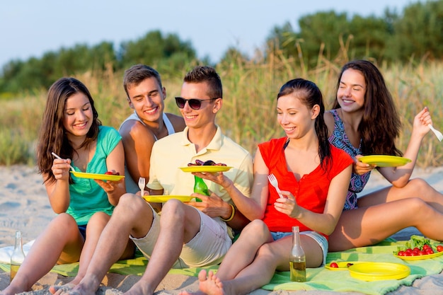 koncepcja przyjaźni, szczęścia, wakacji, wakacji i ludzi - grupa uśmiechniętych przyjaciół siedzących na plaży