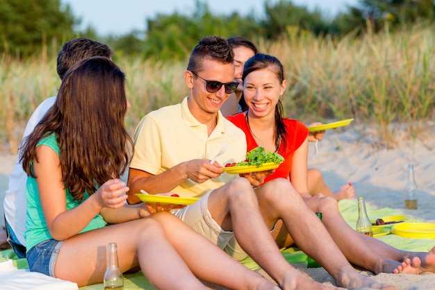 koncepcja przyjaźni, szczęścia, wakacji, wakacji i ludzi - grupa uśmiechniętych przyjaciół siedzących na plaży