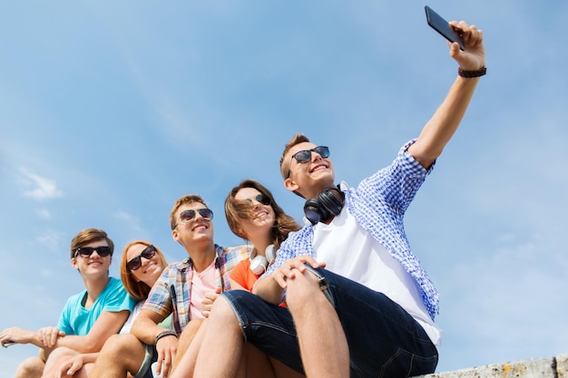 Koncepcja Przyjaźni, Wypoczynku, Lata, Technologii I Ludzi - Grupa Szczęśliwych Przyjaciół Ze Smartfonem Robiących Selfie Na Zewnątrz