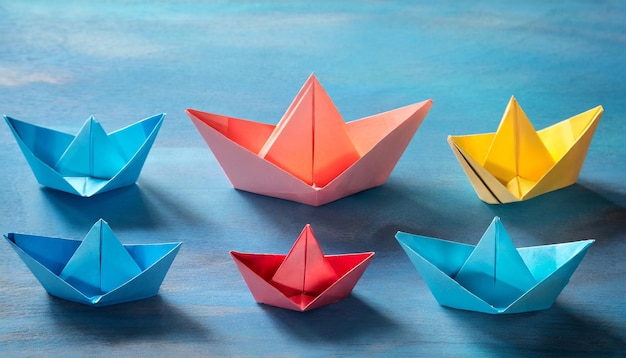 Koncepcja przywództwa i pracy zespołowej kolorowe papierowe łodzie na niebieskim