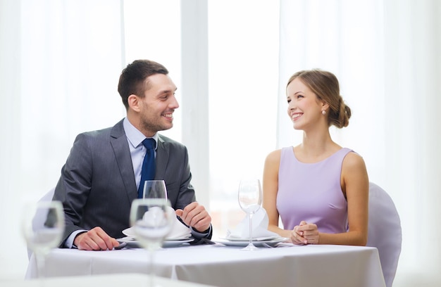 koncepcja restauracji, pary i wakacji - uśmiechnięta para patrząca na siebie w restauracji