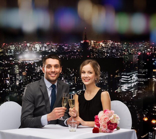 koncepcja restauracji, pary i wakacji - uśmiechnięta para z lampką szampana patrząca na siebie w restauracji