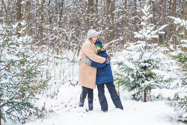 Koncepcja rodzicielstwa, zabawy i sezonu - szczęśliwa matka i syn zabawy i gry ze śniegiem w zimowym lesie.