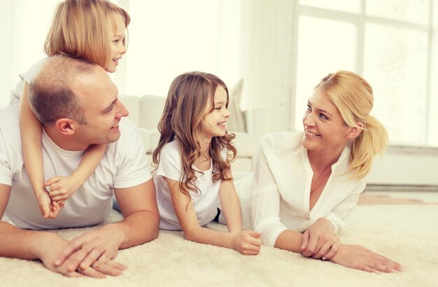 Zdjęcie koncepcja rodziny, dzieci i domu - uśmiechnięta rodzina z dwiema małymi dziewczynkami leżącymi na podłodze w domu