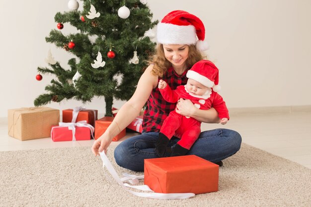 Koncepcja rodziny, dzieciństwa i Bożego Narodzenia - portret szczęśliwej matki i uroczego dziecka w garniturze Świętego Mikołaja.