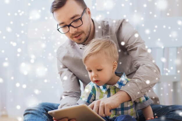 koncepcja rodziny, dzieciństwa, ojcostwa, technologii i ludzi - szczęśliwy ojciec i syn z komputerem typu tablet PC grając w domu na śniegu
